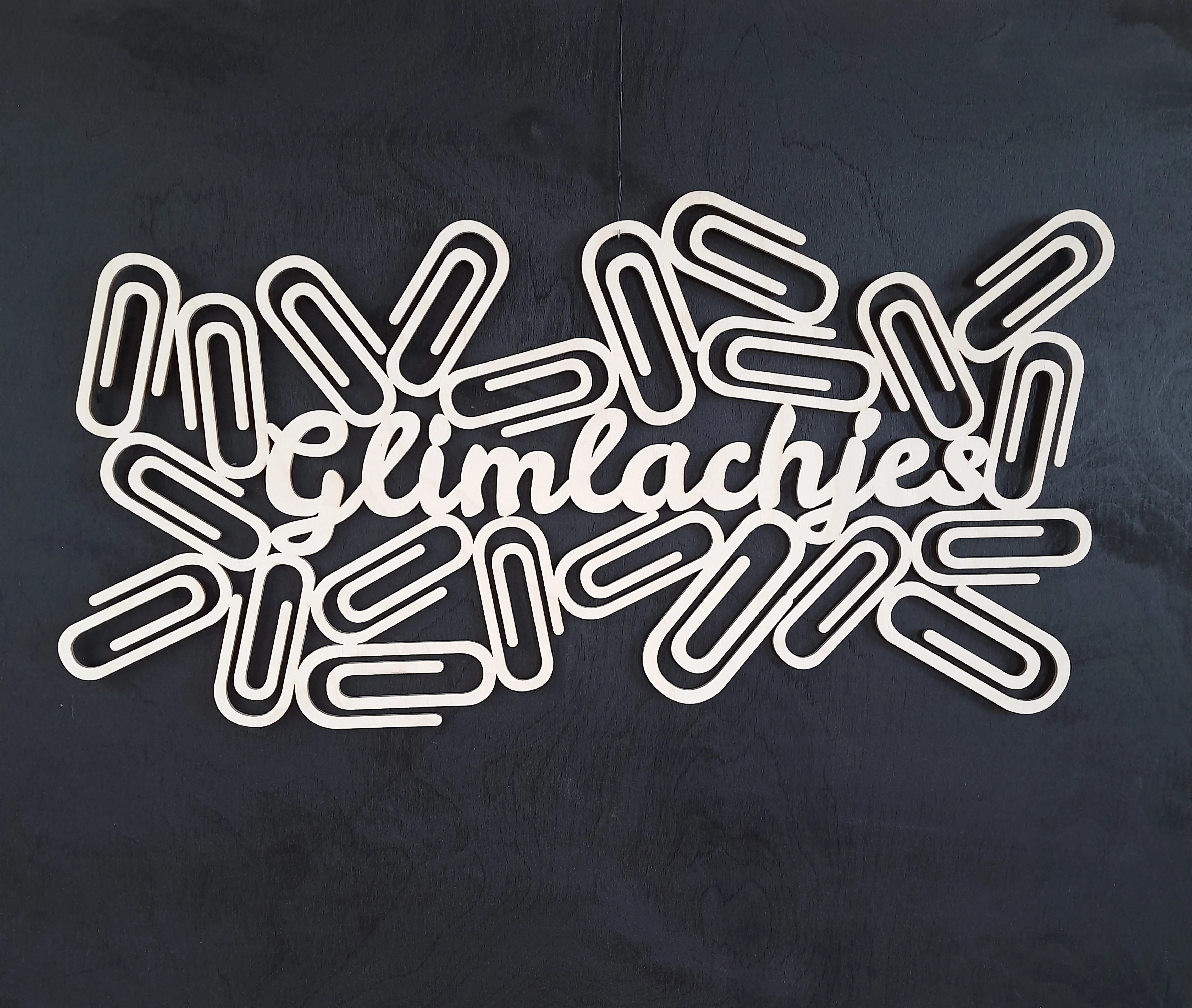 houten paperclips rond de tekst "glimlachjes". Bedoeld als fotohouder aan een wand.