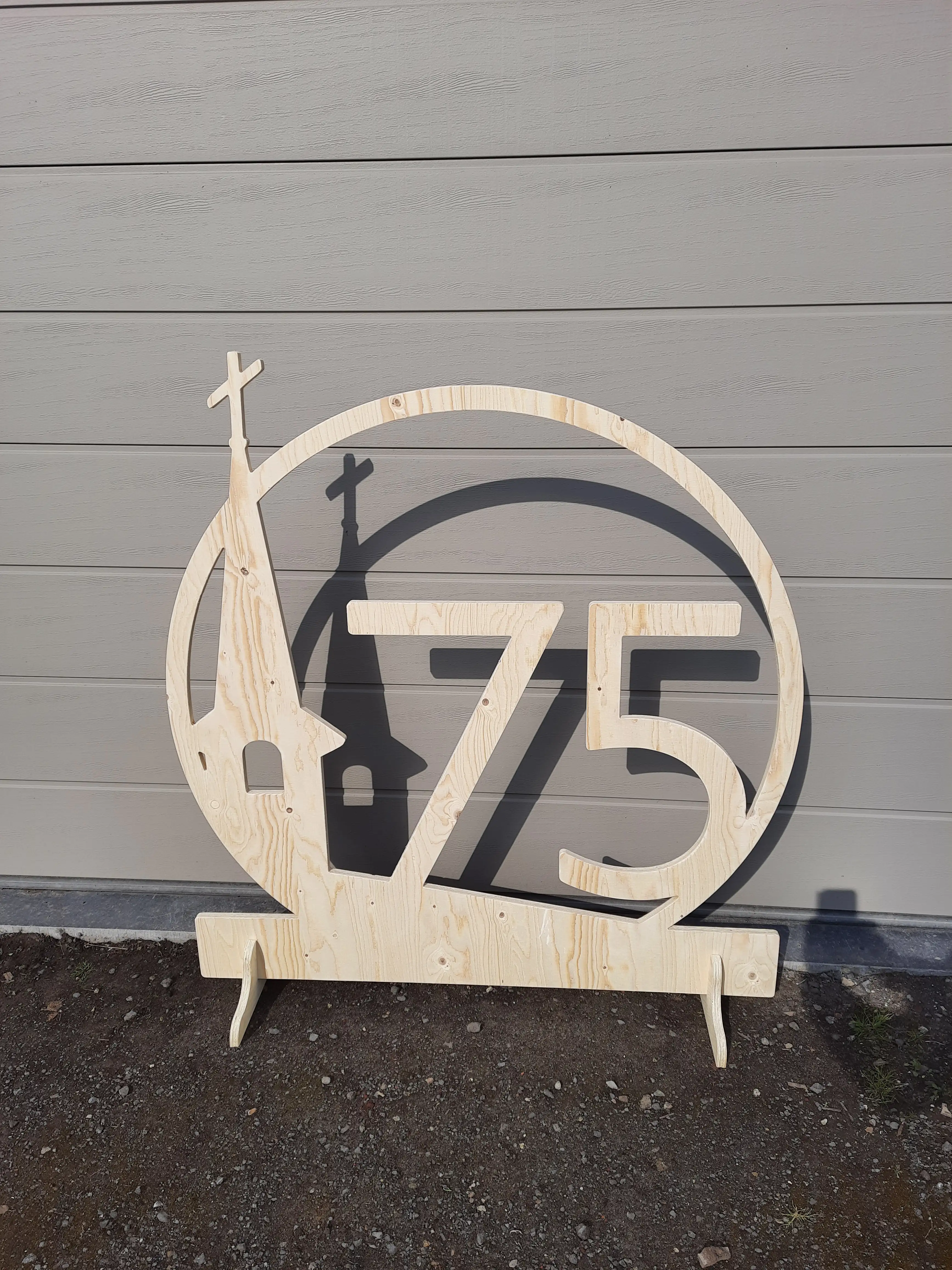 Logo "Kruikerke 75" in blanco hout.