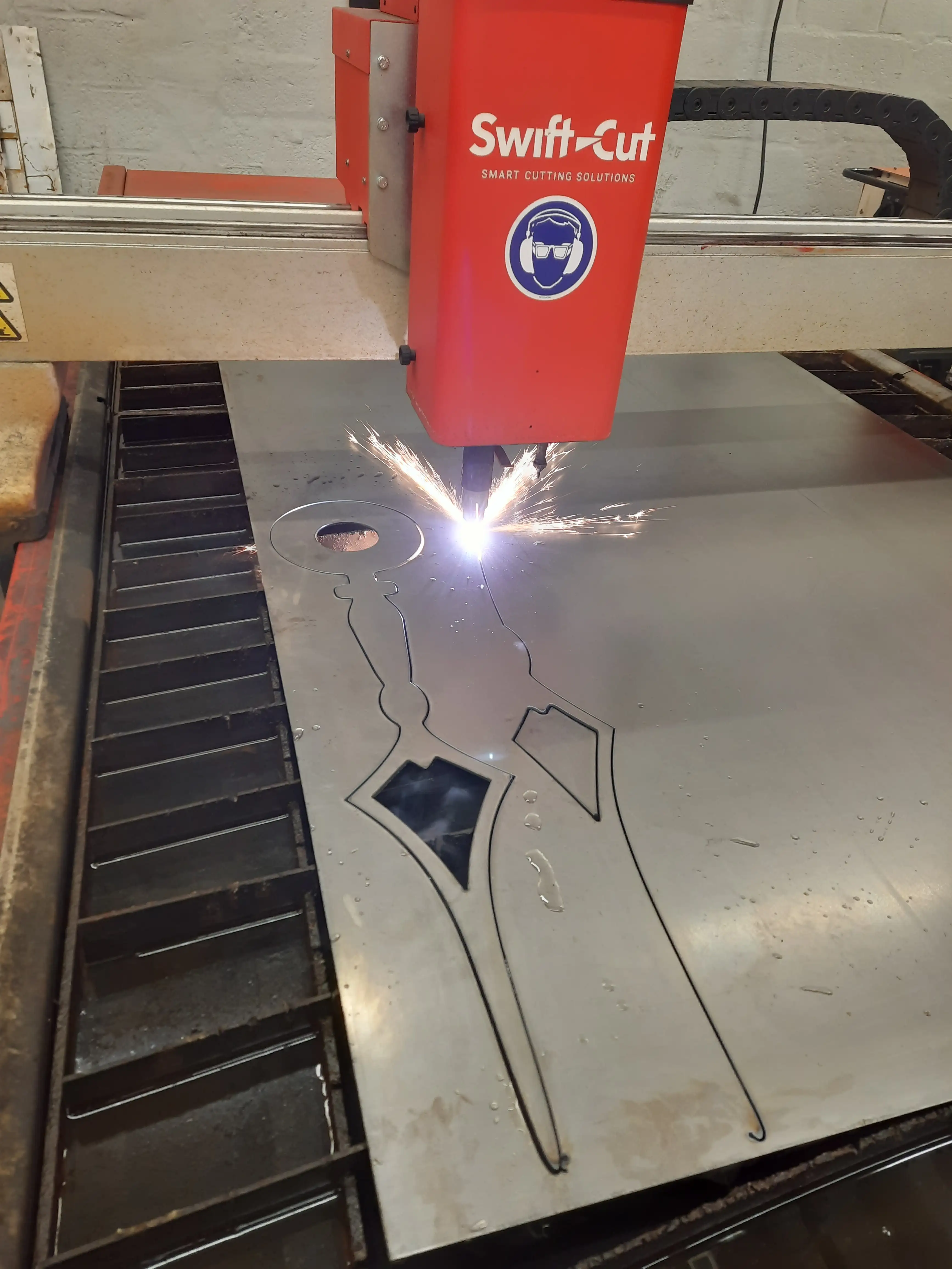 een plasmabrander snijdt met een elektrische vonk door een staaplaat. Op de foto snijdt hij grote wijzers van een ouderwerst uurwerk uit.